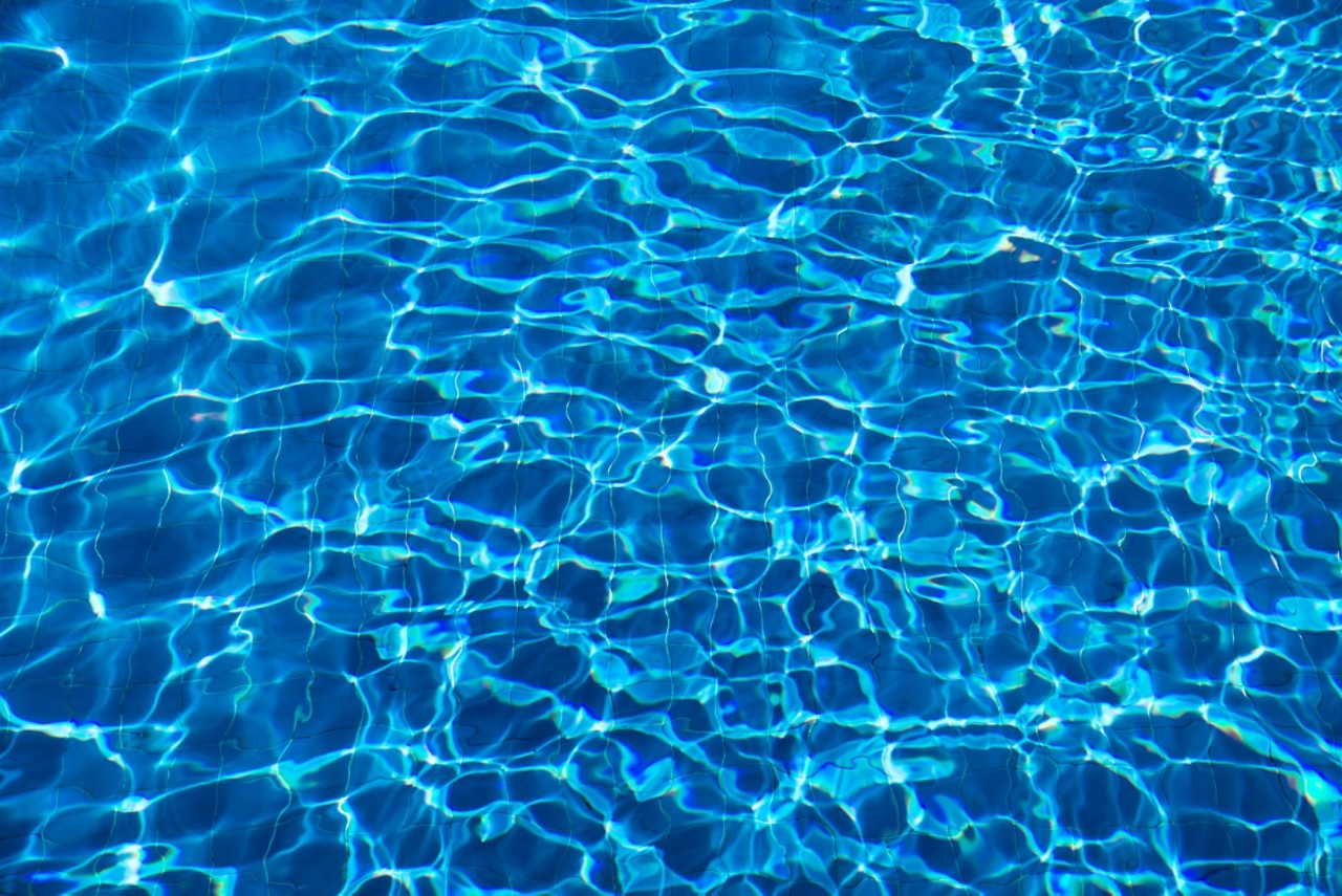 特写的蓝色反射涟漪水在游泳池＂class=